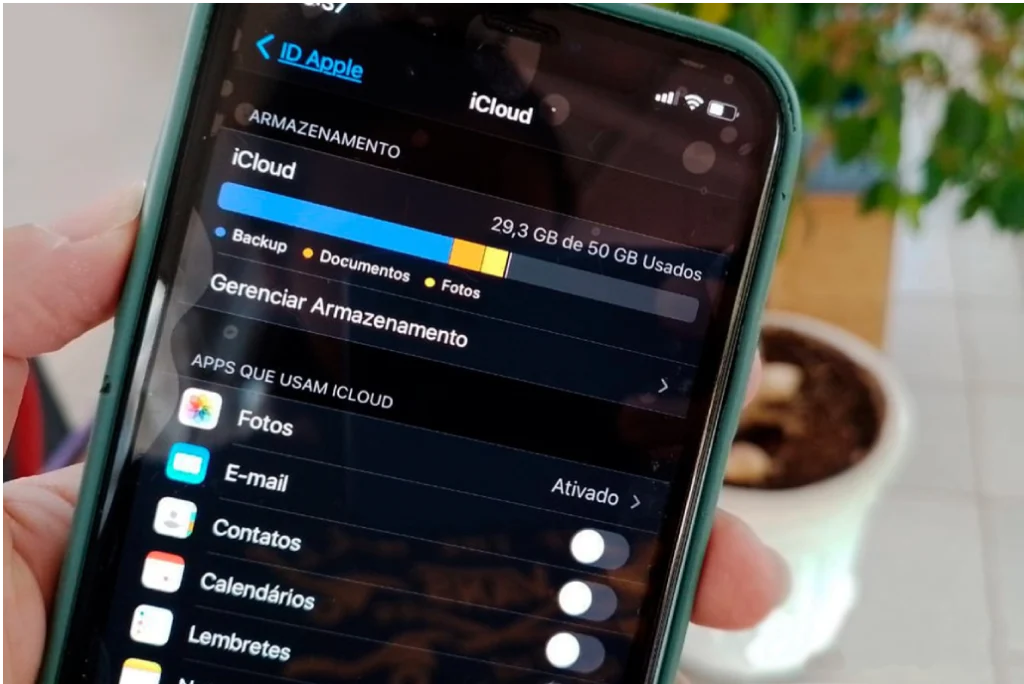 Um telefone segurando a mão exibe o espaço do iCloud com uma lista de programas disponíveis