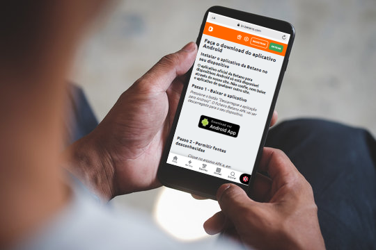 Uma mão segurando um smartphone exibindo a página do cassino para baixar o aplicativo para Android